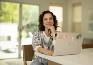 Andrea Ferretti looking at the camera with a laptop open on the table in front of her