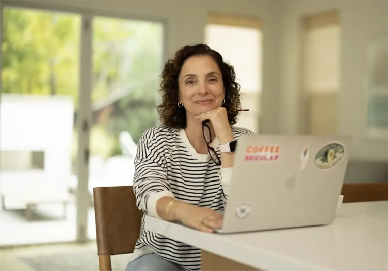 Andrea Ferretti looking at the camera with a laptop open on the table in front of her