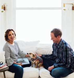 Jason Crandell and Andrea Ferretti sitting on a couch with a dog