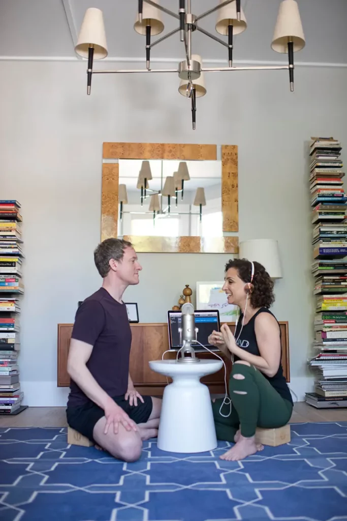 Jason Crandell and Andrea Ferretti sitting on the floor, recording a Yogaland episode