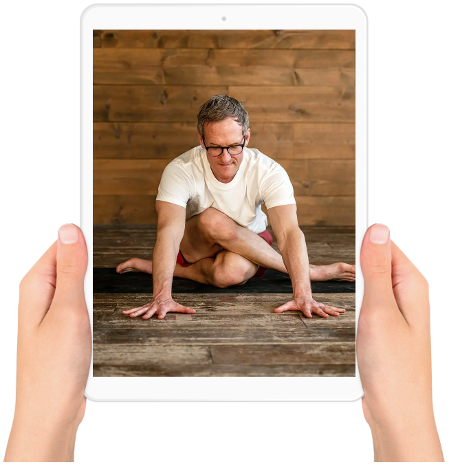 Hands holding an iPad with Jason Crandell in yoga pose on the screen