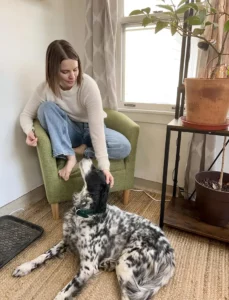 Erin Wallace sitting on a chair with a dog at her feet