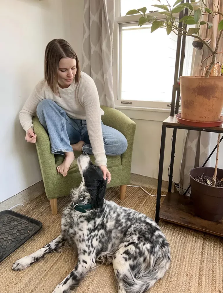 Erin Wallace sitting on a chair with a dog at her feet