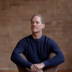 Jason Crandell sitting in a navy shirt gazing off camera